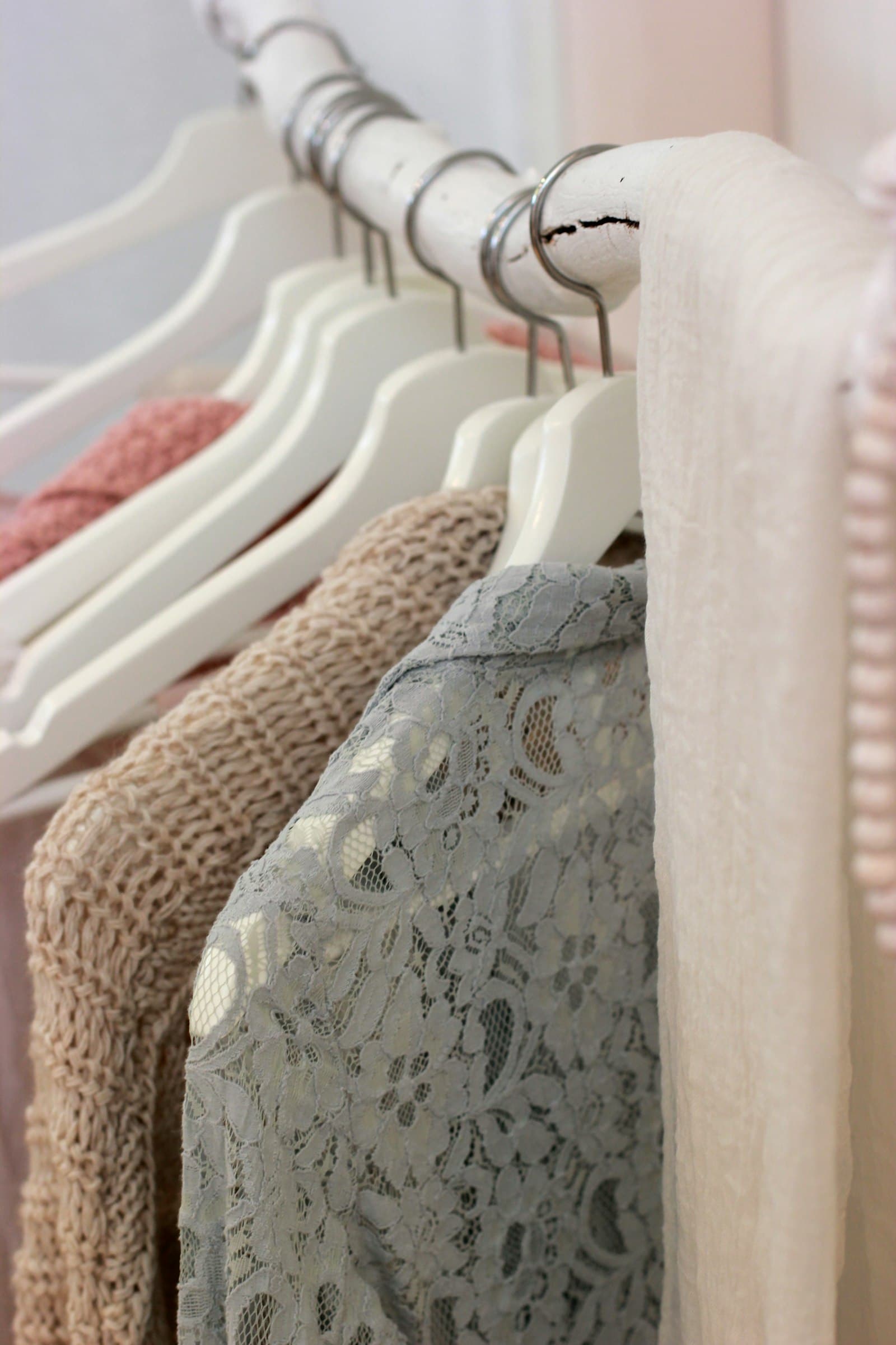 Row of garments on wooden hangers along a rail