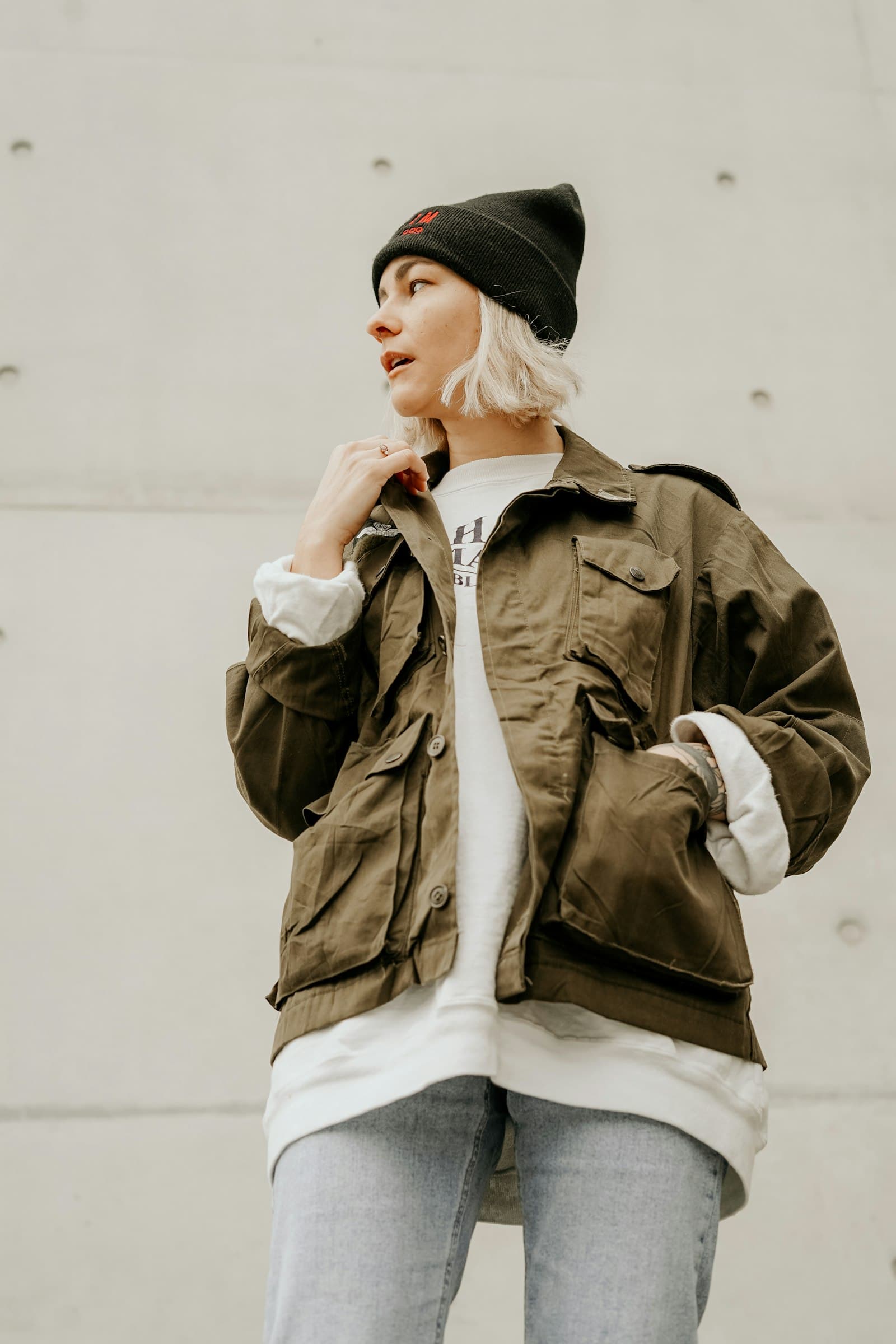 Woman wearing an oversized olive bomber jacket with a knit beanie